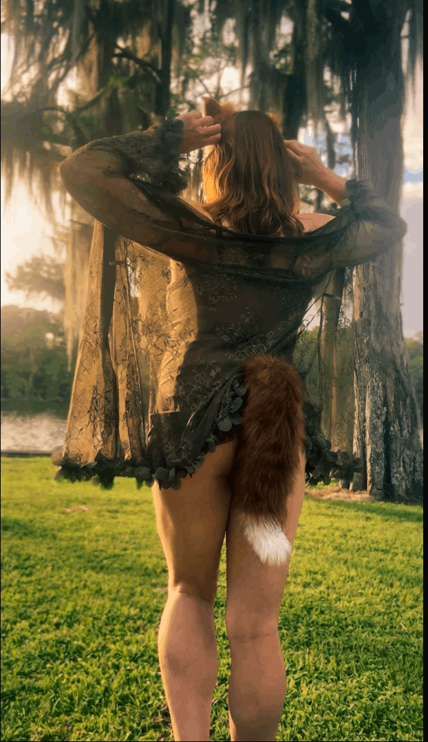 Person in a forest with a fox tail and ears