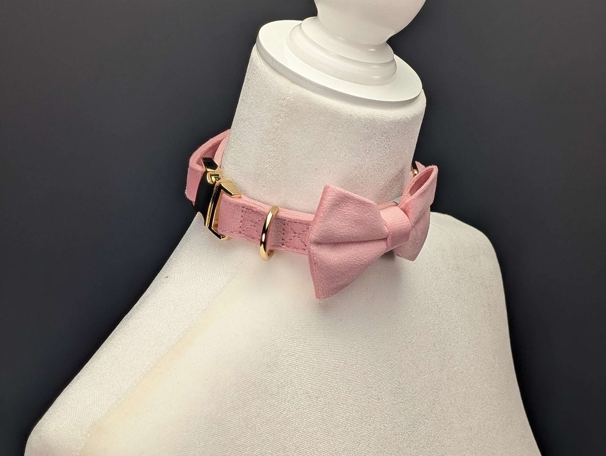 Pink dog collar with a bow on a mannequin against a dark background
