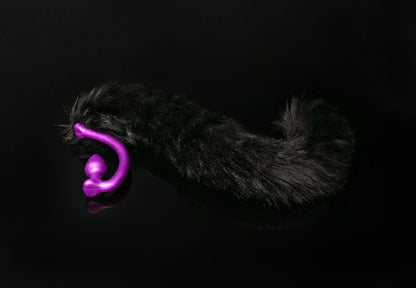Long hair, black cat tail butt plug made of silicone and faux fur, but the plug is hooked so when worn, the tail sits at the bottom of the lumbar area. It’s laying flat on a black background.::Purple
