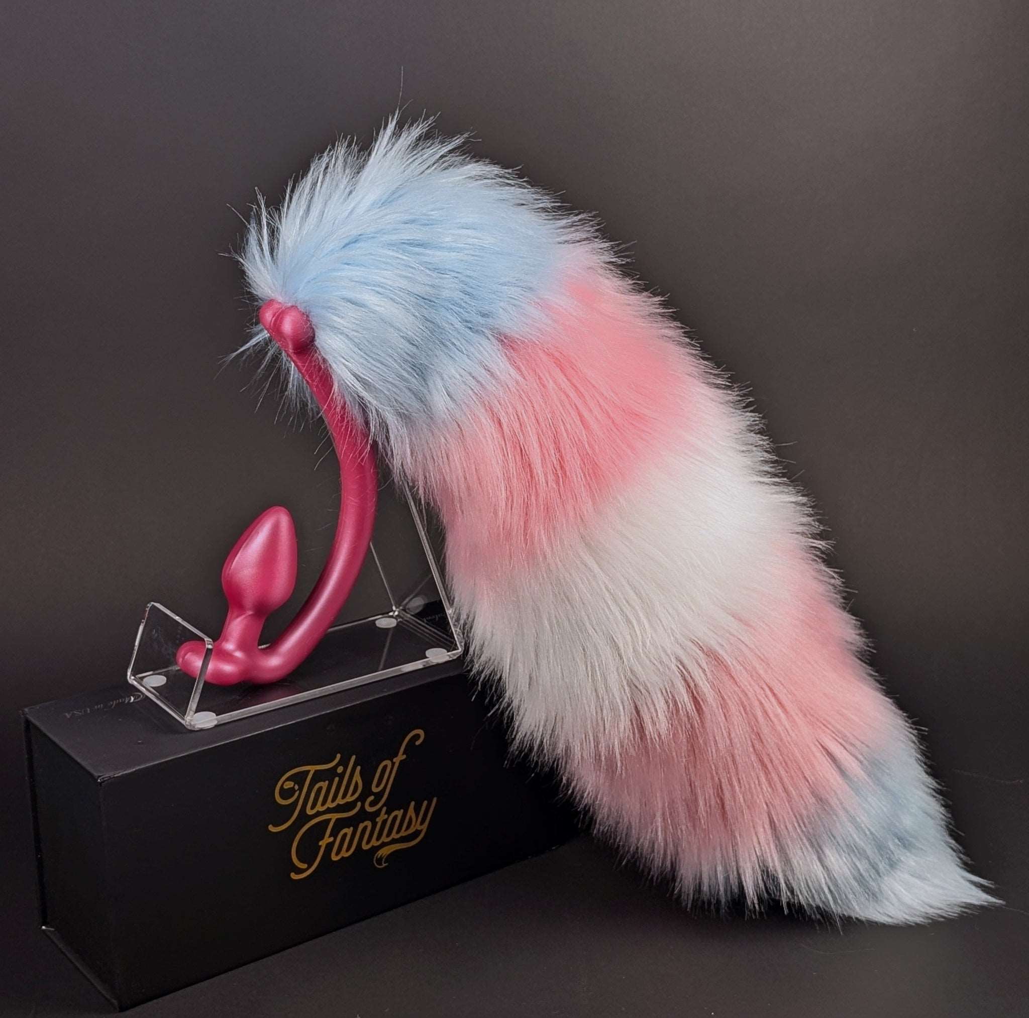 Multi colored raccoon tail butt plug.  Blue, pink and white.  The same colors as the trans pride flag. It is on a pink tail plug.